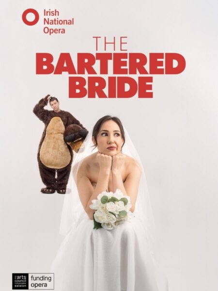 Smetana's The Bartered Bride - A bride in white dress holds flowers, looking thoughtful. Behind her, a man in a bear costume stands with his hand on his head, looking confused. Text reads "Irish National Opera: The Bartered Bride."